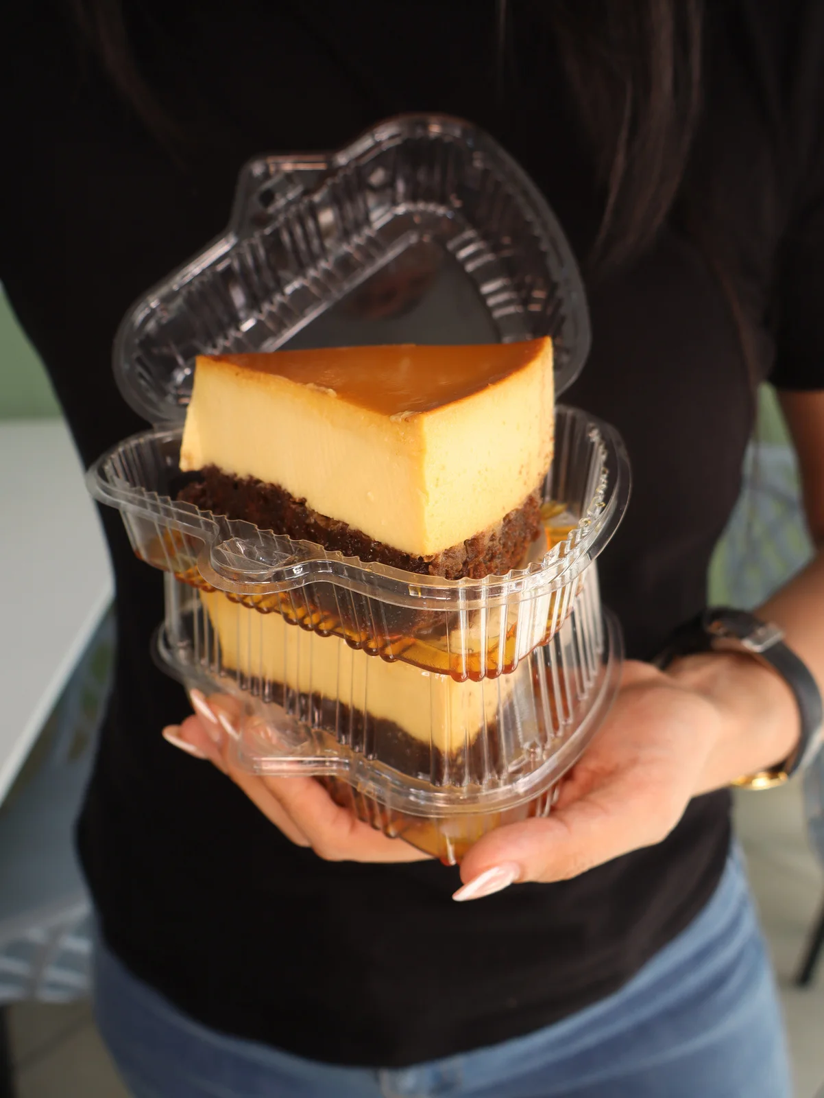 Una mano sostiene envases transparentes con porciones de cheesecake.