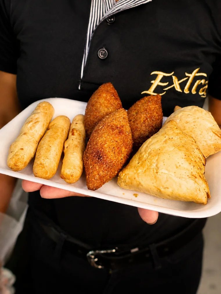 Una persona presenta una bandeja con bocadillos fritos.