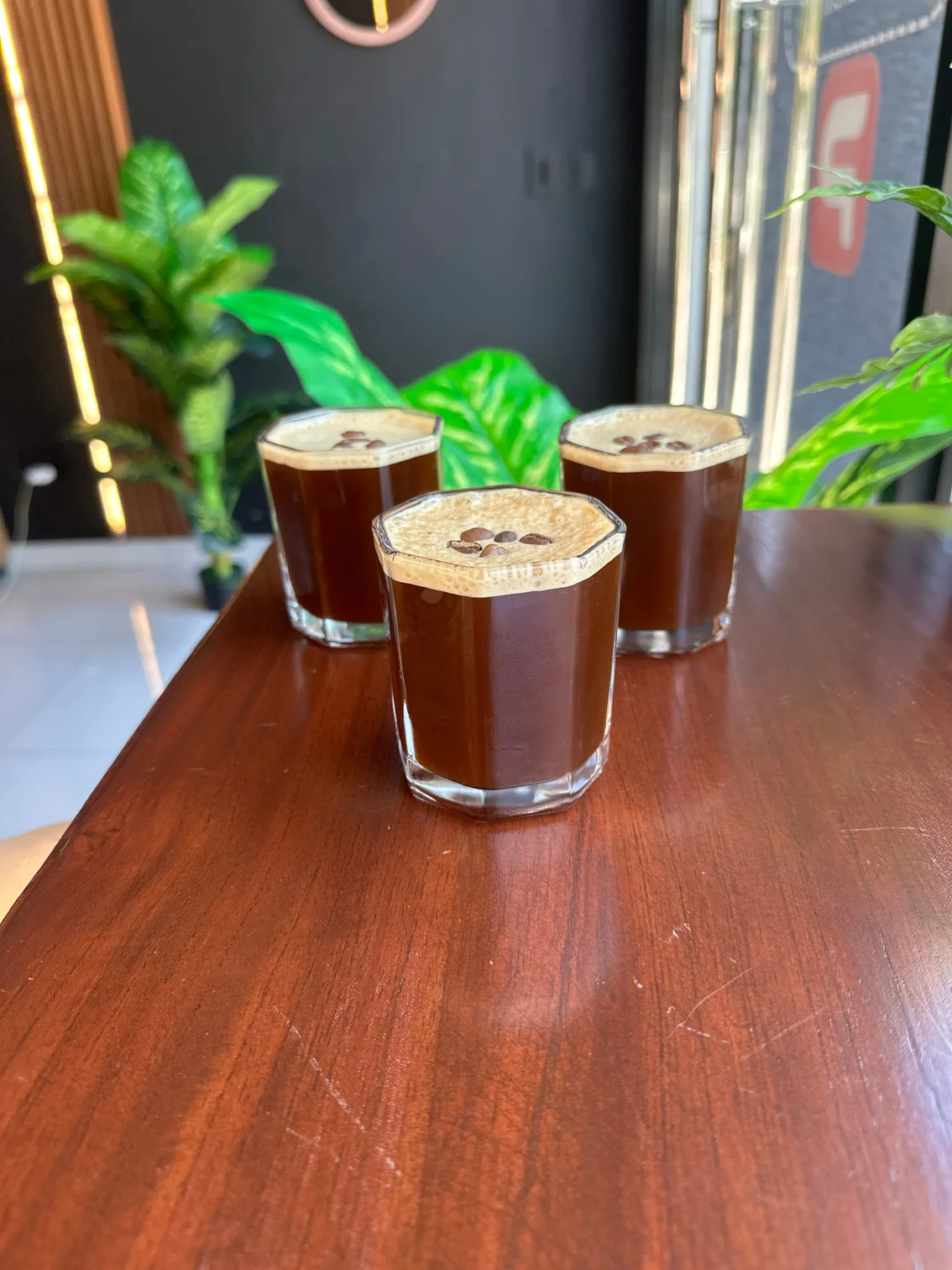 Tres vasos con bebida oscura y espuma sobre una mesa.